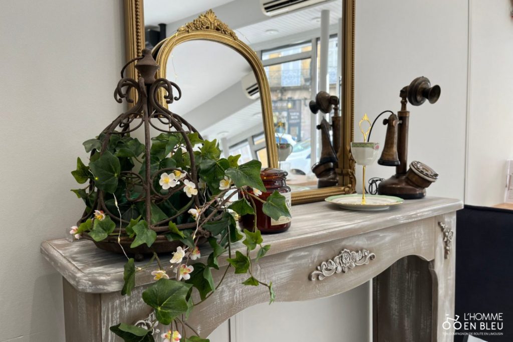 Une partie de la décoration du salon : une fausse cheminée en bois, avec deux miroirs dorés, un ancien téléphone des années 1930, agrémenté d'une plante grimpante.